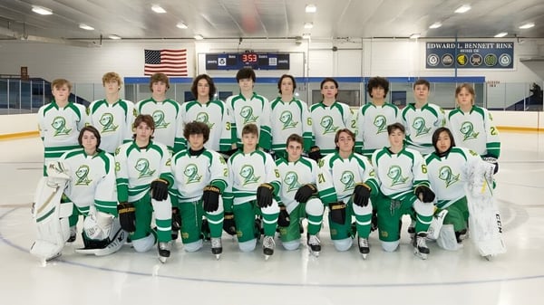 Eine Gruppe junger Hockeyspielerinnen und Hockeyspieler posiert auf der Eisbahn auf dem Campus der Notre Dame de la Baie Academy.