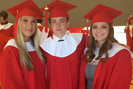 Drei Schülerinnen tragen rote Abschlusskleidung auf dem Campus der Nottawasaga Pines Secondary School.