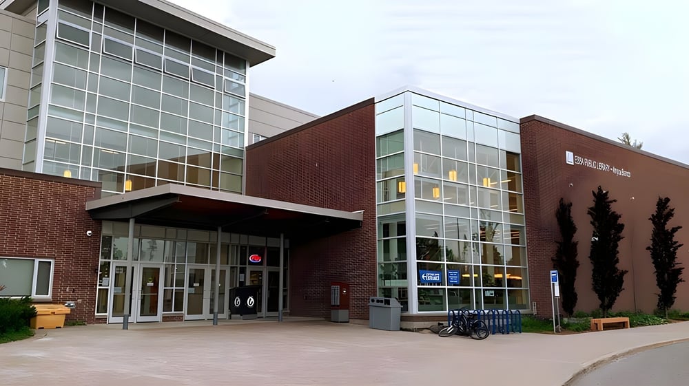 Das moderne mehrstöckige Gebäude der Nottawasaga Pines Secondary School mit Glasfassade und Ziegelaußenwand steht an einem gepflasterten Weg.