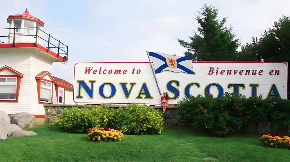 Das Willkommensschild von Nova Scotia mit Leuchtturmstruktur und kanadischer Flagge auf dem Gelände des Nova Scotia French Program.