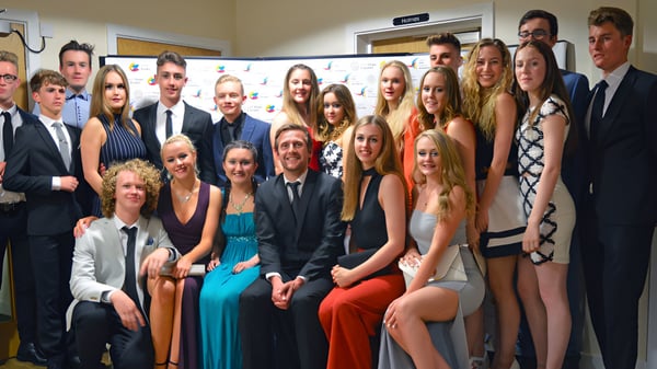 Eine Gruppe von Schülerinnen und Schülern des Oak Leaf Studio posiert gemeinsam vor einem Schulgebäude.