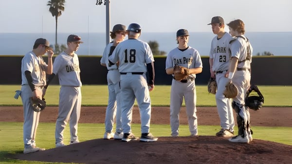 Eine Gruppe von Baseballschülern steht auf dem Baseballfeld des Oak Park Unified School District vor Palmen und klarem Himmel.