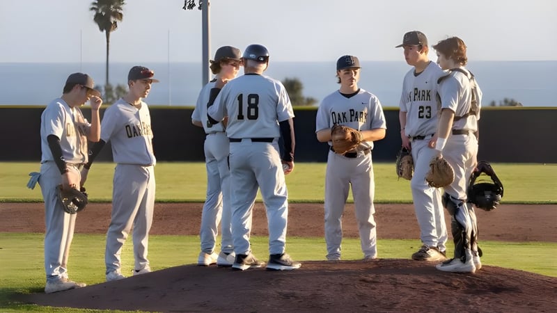 Eine Gruppe von Baseballschülern steht auf dem Baseballfeld des Oak Park Unified School District vor Palmen und klarem Himmel.