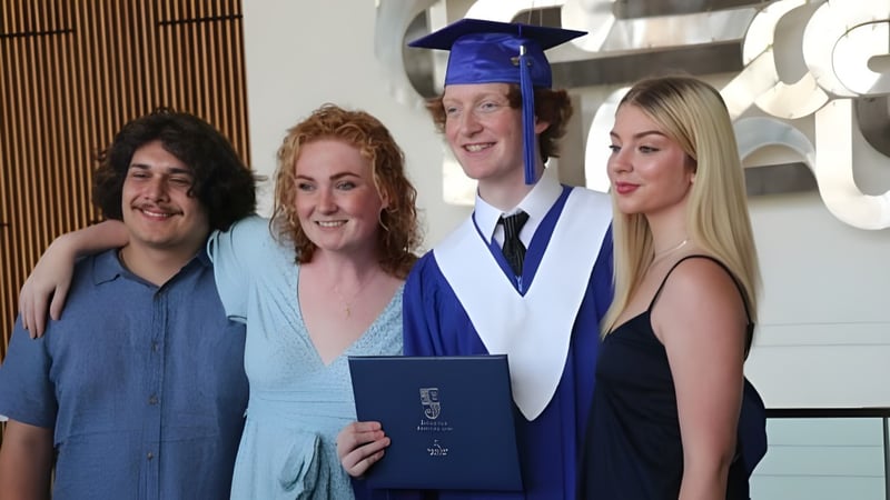 Vier Personen, darunter ein Absolvent in Talar, stehen gemeinsam bei einer Abschlussfeier der Oak Park High School.