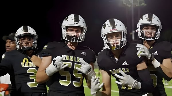 Eine Gruppe von Football-Spielern in Uniform steht auf dem Spielfeld unter hellen Flutlichtern auf dem Gelände des Oak Park Unified School District.