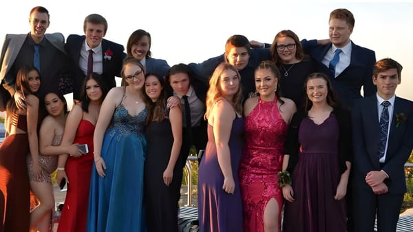 Eine Gruppe von gut gekleideten Personen steht gemeinsam vor einer landschaftlichen Kulisse auf dem Gelände der Oakbank Area School.