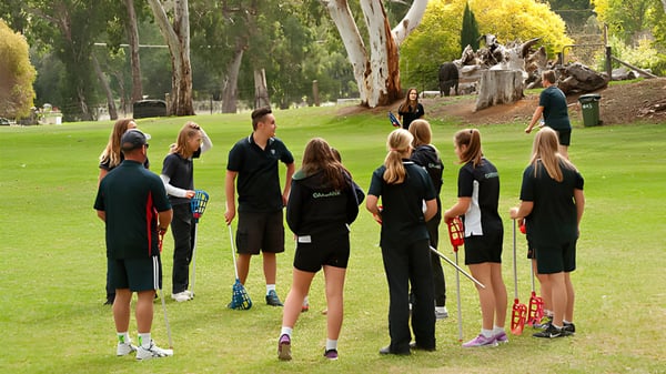 Eine Gruppe von Schülerinnen und Schülern des Oakbank Area School steht auf einem grünen Feld umgeben von Bäumen.