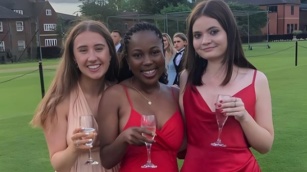 Drei Schülerinnen der Oakham School stehen auf einem Grasfeld und halten Sektgläser.