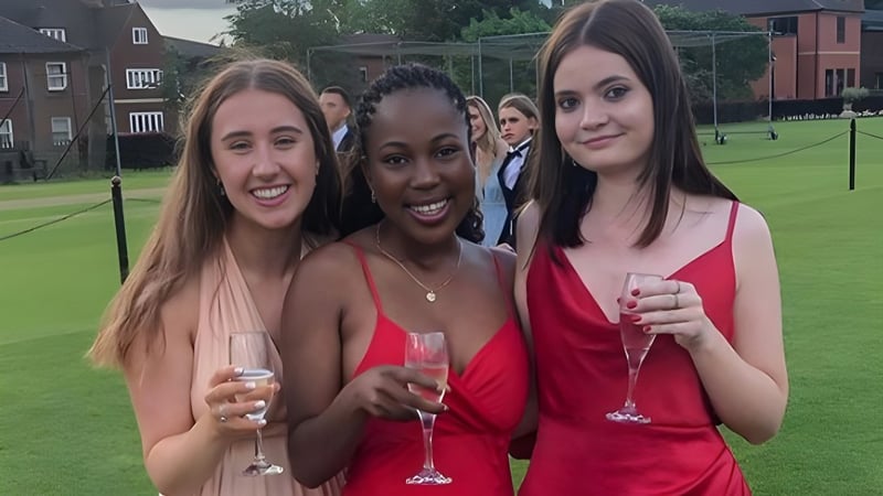 Drei Schülerinnen der Oakham School stehen auf einem Grasfeld und halten Sektgläser.