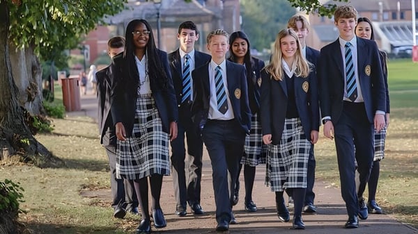 Eine Gruppe Schülerinnen und Schüler der Oakham School geht gemeinsam auf einem von Bäumen und Grün umgebenen Weg.