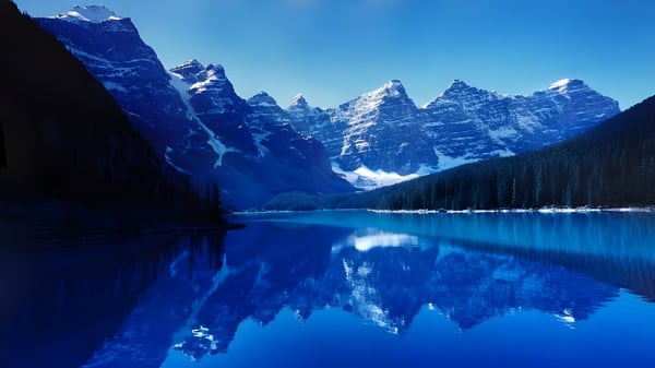 Ein klarer alpiner See spiegelt die verschneiten Berge in der Umgebung der Oakridge Secondary School wider.