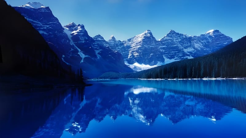 Ein klarer alpiner See spiegelt die verschneiten Berge in der Umgebung der Oakridge Secondary School wider.