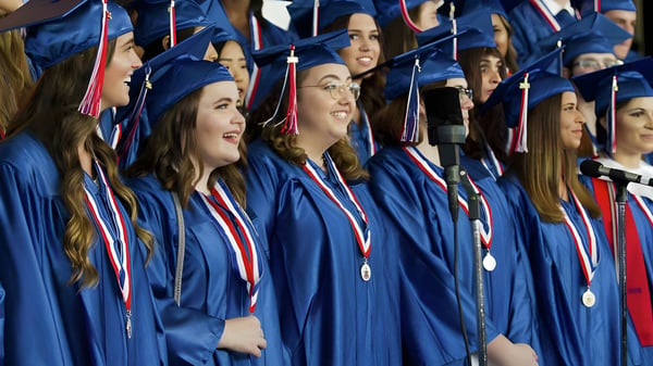 Absolventen der Oakridge Secondary School stehen in blauen Talaren bei einer Abschlussfeier zusammen.