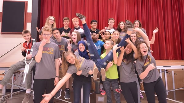 Eine Gruppe von Schülerinnen und Schülern posiert vor einem roten Vorhang auf dem Campus der Oakridge Secondary School.