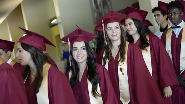 Eine Gruppe von Absolventen der Oaks Christian School in roten Talaren steht zusammen im Flur und feiert ihren Abschluss.