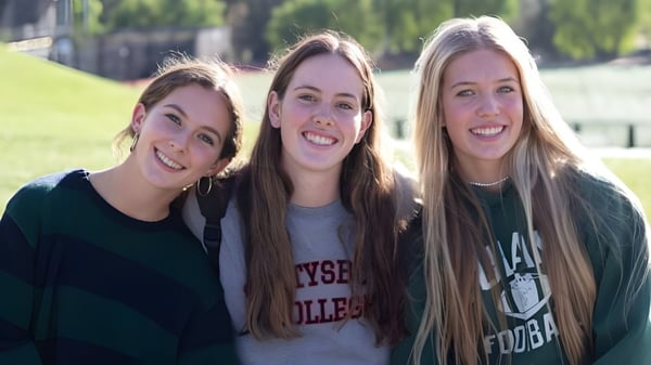 Drei Schülerinnen mit langen gewellten Haaren stehen zusammen auf einer Wiese auf dem Gelände der Oaks Christian School.