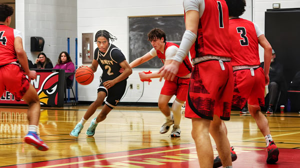Schüler der Oakville Trafalgar High School spielen ein Basketballspiel auf einem Holzboden vor Zuschauern.