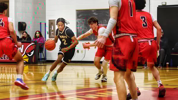 Schüler der Oakville Trafalgar High School spielen ein Basketballspiel auf einem Holzboden vor Zuschauern.