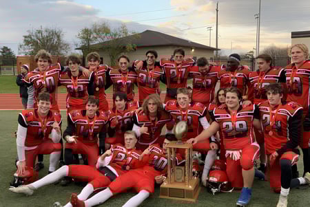 Eine Gruppe junger Fußballspieler der Oakville Trafalgar High School posiert mit einer Trophäe auf einem Sportfeld.