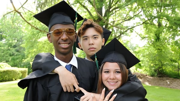 Drei Absolventinnen und Absolventen der Oakwood Friends School posieren gemeinsam im grünen Außenbereich.