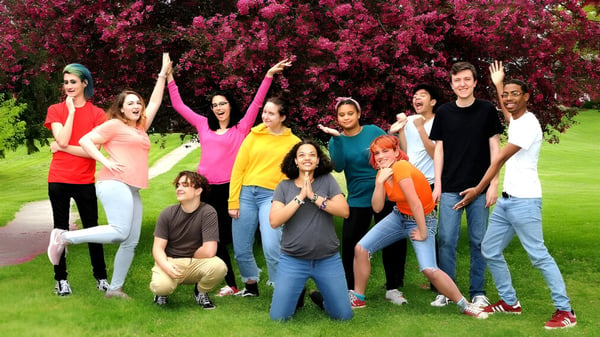 Eine Gruppe von Schülerinnen und Schülern der Oakwood Friends School steht in einem Feld vor blühenden rosa Bäumen.