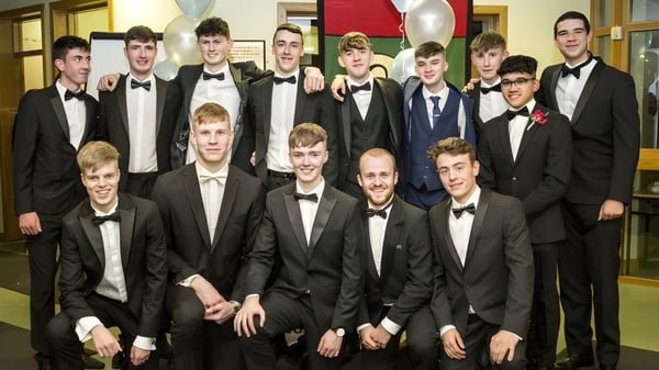 Eine Gruppe junger Männer im formellen Anzug posiert im Flur des Oatlands College mit Dekoration und Luftballons im Hintergrund.