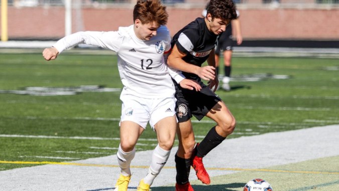 Zwei Fußballspieler kämpfen auf dem Spielfeld um den Ball auf dem Campus des Oatlands College.