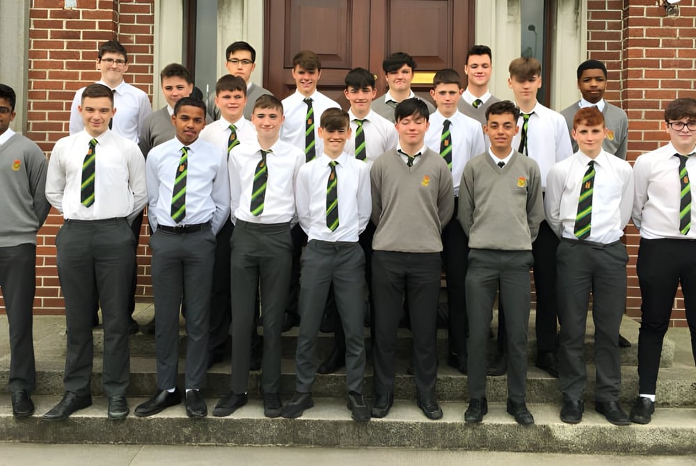 Eine Gruppe von Schülern steht auf der Treppe eines Backsteingebäudes auf dem Campus des Oatlands College.