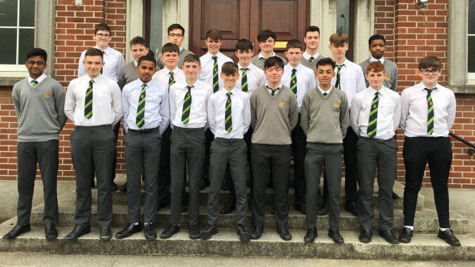 Eine Gruppe Schüler in Schuluniformen steht vor einem Backsteingebäude auf dem Campus des Oatlands College.