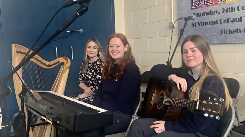 Drei Schülerinnen des O’Carolan College treten gemeinsam auf der Bühne mit Keyboard und Gitarre auf.