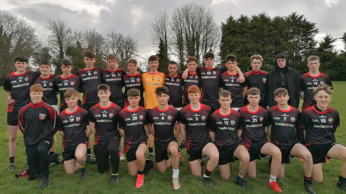 Eine Gruppe junger Fußballspielerinnen und Spieler posiert gemeinsam auf dem Sportplatz des O’Carolan College.