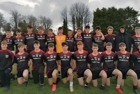 Eine Gruppe von Schülerinnen und Schülern des O’Carolan College posiert gemeinsam auf einem Fußballfeld mit Bäumen im Hintergrund.