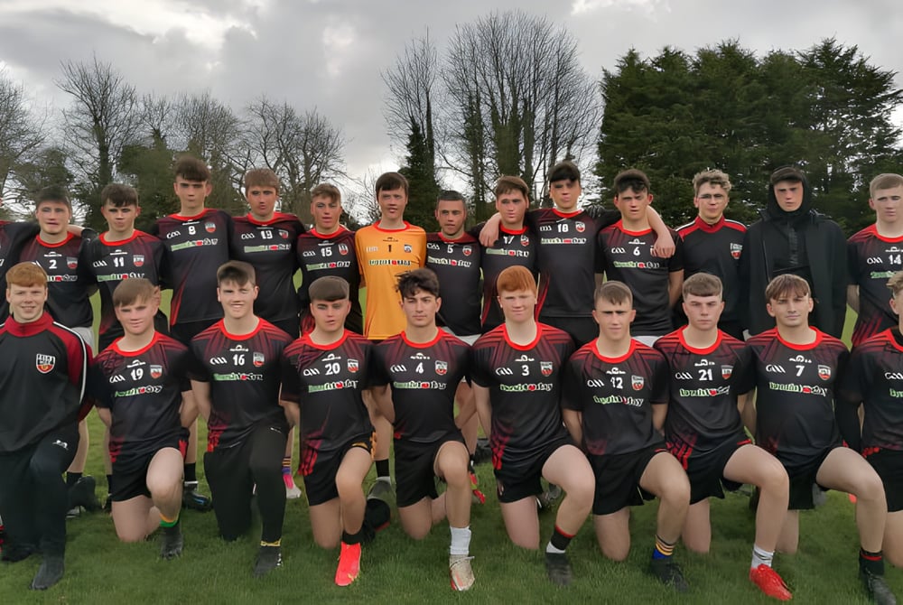 Eine Gruppe von Schülerinnen und Schülern des O’Carolan College posiert gemeinsam auf einem Fußballfeld mit Bäumen im Hintergrund.