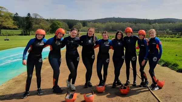 Schüler des O’Carolan College tragen Neoprenanzüge und Helme bei einer Wassersportaktivität im Freien.