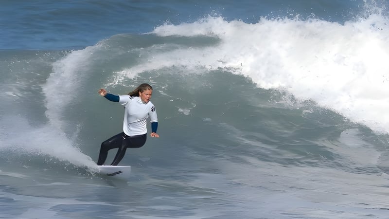 Ein Surfer reitet eine große Welle im Ozean vor dem Hintergrund eines bewölkten Himmels auf dem Odenz Programm.