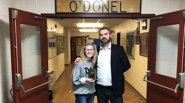 Ein Mann und eine Frau stehen im Flur der O'Donel High School vor einem Schild mit dem Schulnamen.