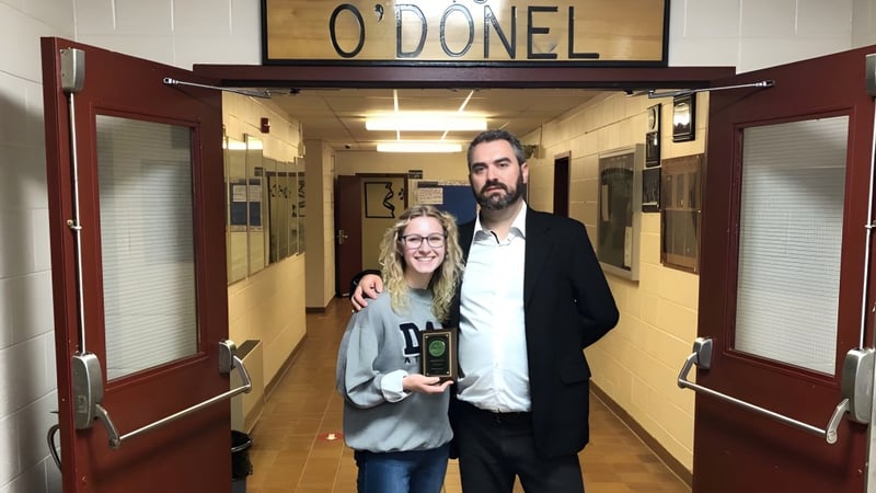 Ein Mann und eine Frau stehen im Flur der O'Donel High School vor einem Schild mit dem Schulnamen.