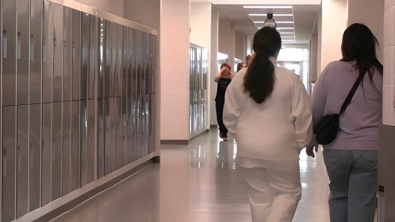 Schüler gehen den Flur mit Spinden an der Wand in der Ohpaho Secondary School entlang.