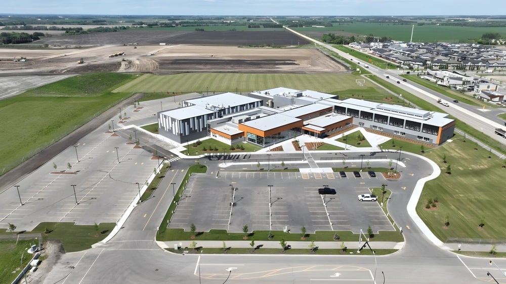 Das moderne Gebäude der Ohpaho Secondary School liegt umgeben von Feldern und einer Straße mit angrenzendem Parkplatz.