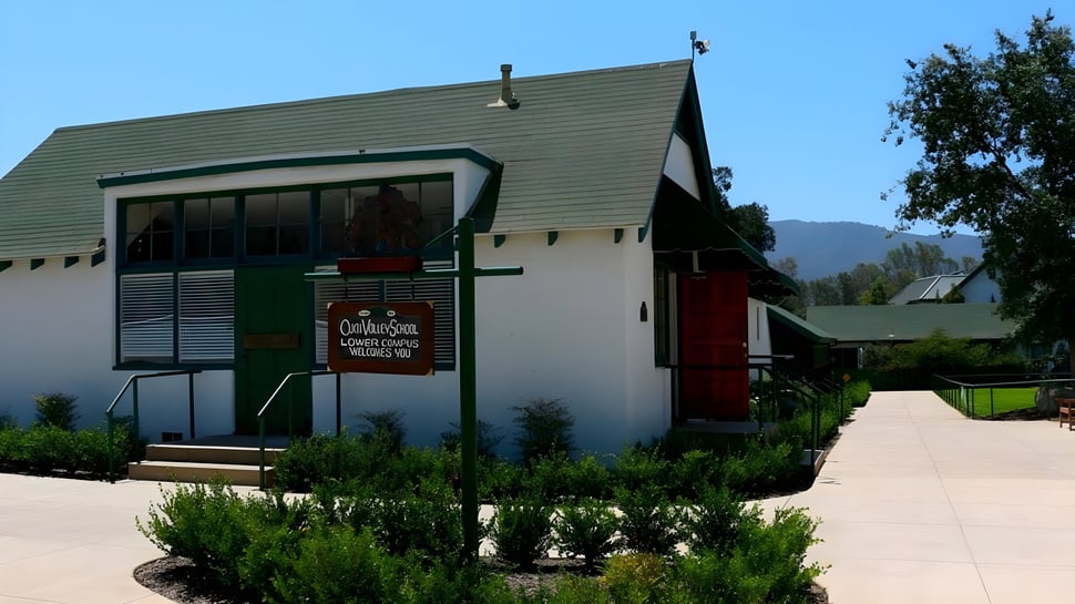 Das gruenbedachte Gebaeude des Carmel Valley Tasting Room auf dem Gelaende der Ojai Valley School mit bewachsenen Bergen im Hintergrund.