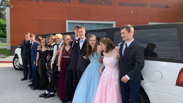 Eine Gruppe Schüler steht vor dem Gebäude der Okanagan Mission Secondary School mit dem Schulnamen am Eingang.