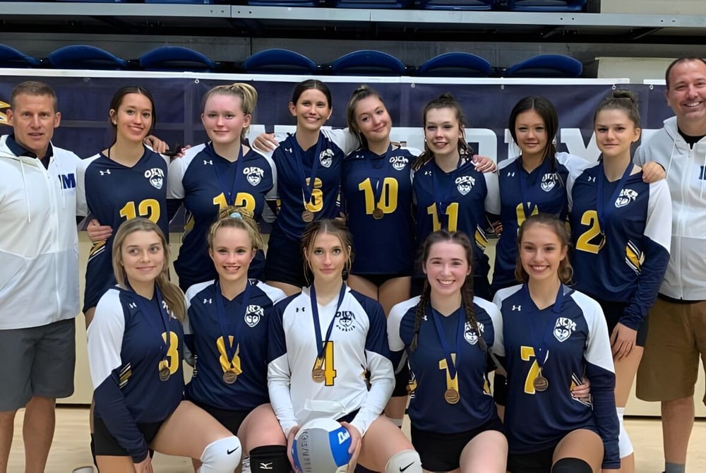 Eine Gruppe junger Sportlerinnen der Okanagan Mission Secondary School posiert gemeinsam in einer Turnhalle.