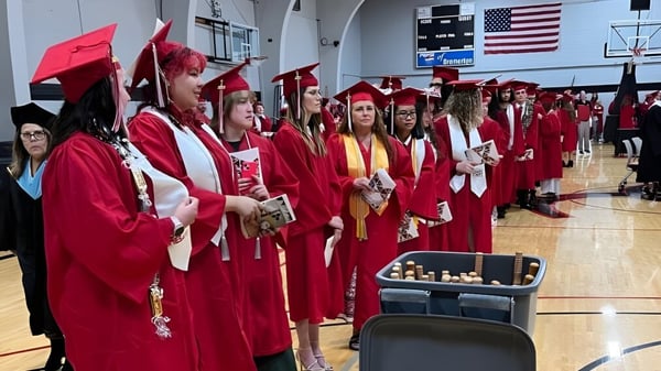Absolventinnen und Absolventen in roten Abschlusskleidern stehen in der Turnhalle des Olympic College.
