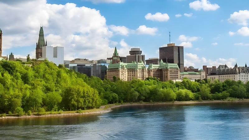 Blick auf das grüne Flussufer mit der Stadtansicht im Hintergrund auf dem Gelände der École secondaire publique Omer-Deslauriers.
