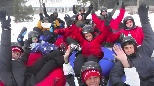 Eine Gruppe von Schülern der École secondaire publique Omer-Deslauriers steht in bunter Winterkleidung draußen im Schnee vor Gebäuden.