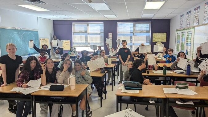 Schüler sitzen in einem Klassenzimmer der École secondaire publique Omer-Deslauriers mit Tischen und Lehrmaterialien an den Wänden.