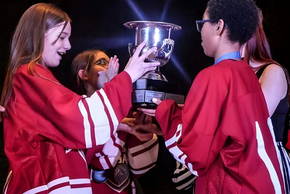 Schüler der École secondaire publique Omer-Deslauriers feiern gemeinsam mit einem Pokal ihren Erfolg.