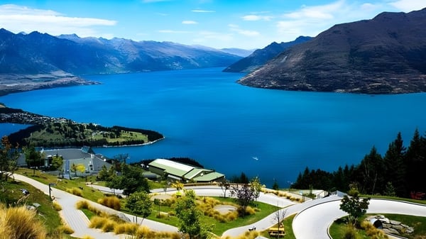 Ein ruhiger See mit Bergen und einem Dorf im Vordergrund, zu sehen in der Nähe der Onehunga High School.