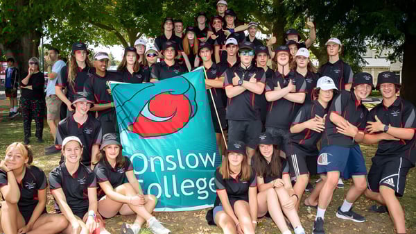 Eine Gruppe von Schülerinnen und Schülern des Onslow College steht im Freien und hält eine Flagge mit dem Namen der Schule.