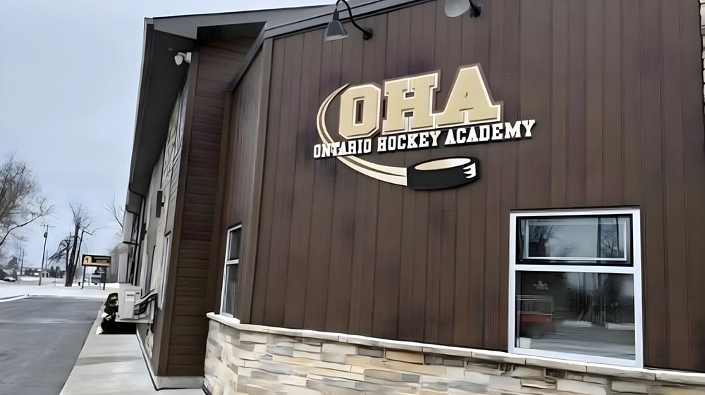 Das Gebäude der Ontario Hockey Academy mit Holzverkleidung und dem Logo auf der Frontseite ist zu sehen.